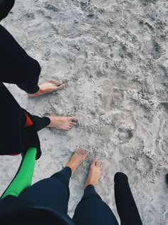 four people standing in the sand with their feet up