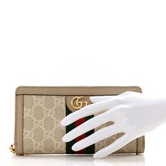 This is an authentic GUCCI GG Supreme Monogram Textured Dollar Calfskin Web Ophidia Zip Around Wallet in Beige, Mystic White, and Oatmeal. This stylish wallet is crafted of Gucci GG monogram coated canvas with a green and red web stripe and brown trim. This wallet features a wrap-around gold zipper and opens to a brown fabric and leather interior with card slots, a zipper compartment, and a bill compartment. Red Web, Gg Monogram, Brown Trim, Brown Fabric, Gucci Wallet, Green And Red, Gold Zipper, Leather Interior, Card Slots