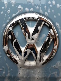 the front emblem of a volkswagen car covered in water and drops of condensation