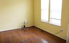 an empty room with hard wood floors and yellow walls