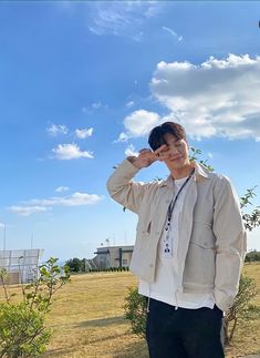 a young man standing on the side of a road talking on a cell phone while holding his hand up to his ear