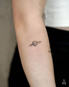 a small saturn tattoo on the arm