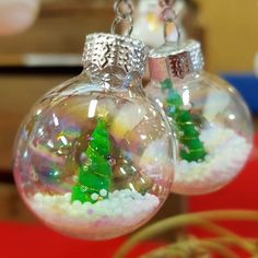 two glass ornaments with small green trees in them