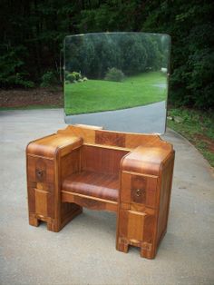 a wooden desk with a mirror on top of it in front of some grass and trees