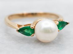 Add a touch of whimsy to your jewelry collection with our Yellow Gold Saltwater Pearl Ring. With elegant pear cut emerald accents, this ring is perfect for adding a pop of color to any outfit. Channel your inner mermaid with this playful and unique piece!Metal: 14K Yellow GoldGem: Saltwater PearlGem Measurements: 6.9 mm, RoundAccents: 2 Emeralds totaling .30 CaratsRing Size: 6Marks: "EH 14K" Stamped on the inside band College Rings, Dream Wedding Ring, Saltwater Pearls, Emerald Ring, Pear Cut, Pearl Ring, Unique Pieces, Gold Rings, Color Pop