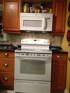 a white stove top oven sitting inside of a kitchen next to wooden cupboards and counter tops