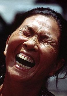 a woman laughing with her eyes closed and mouth wide open