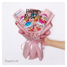 a bouquet of pink roses with happy birthday candies in the center and hand holding it