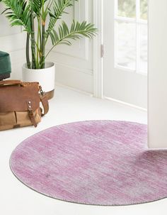 a pink rug in the corner of a room next to a potted plant and luggage