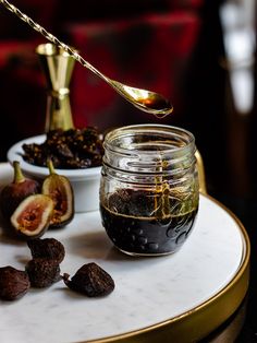 figs and nuts on a table with a spoon in the jar next to them