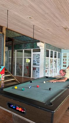 a man leaning over a pool table in a room filled with billiards and arcade games