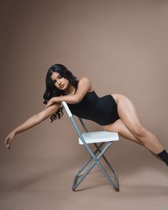 a woman is posing on a chair with her legs spread out and one leg up