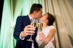 a bride and groom kissing while holding champagne flutes