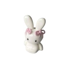 a white ceramic figurine with a pink bow on it's head and ears