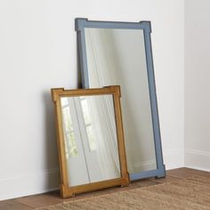 a mirror sitting on top of a wooden floor next to a rug and window sill