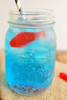 a jar filled with blue liquid and a red fish in it