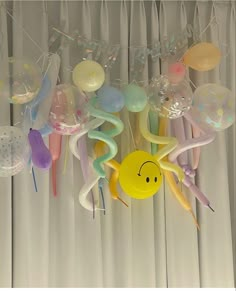 balloons and streamers are hanging from the ceiling in front of a curtain with white drapes