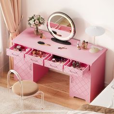 a pink desk with drawers and a mirror