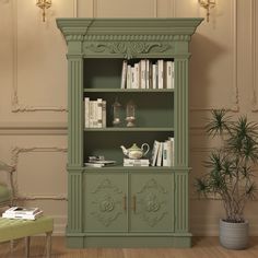 a green bookcase with books on it in a living room next to a chair and potted plant