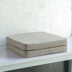 a square cushion sitting on top of a white shelf