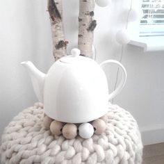 a white teapot sitting on top of a blanket next to some birch tree trunks