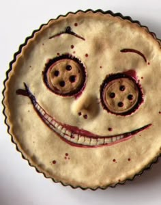 an odd looking pie with eyes and mouth painted on it's side, sitting on a white surface