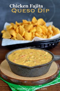 a bowl of chips sitting on top of a wooden table next to a plate of tortilla chips