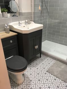 a bathroom with a toilet, sink and shower stall in the corner next to a tiled floor