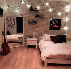 a bedroom with white brick walls and string lights strung over the bed, along with a guitar