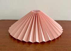 a pink paper fan sitting on top of a wooden table