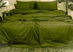 a bed covered in green sheets and pillows