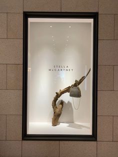 a window display with an old tree branch in the center and a lamp hanging from it's side