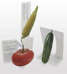 a tomato, cucumber and ear of corn are on display at an exhibition