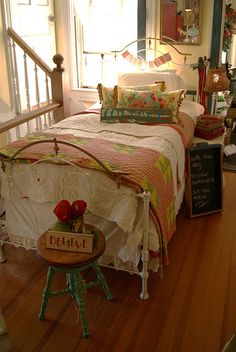 a bed sitting on top of a hard wood floor next to a table with a sign