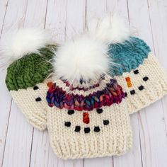 three knitted hats with white fur pom - poms on top of each other