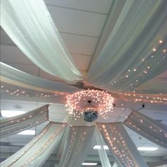 the ceiling is decorated with white drapes and lights