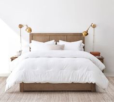 a bed with white sheets and pillows in a room