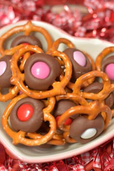 chocolate covered pretzels and candy coated pretzels in a heart shaped bowl