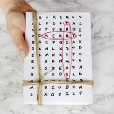 a person holding a piece of paper with a cross drawn on it next to a string