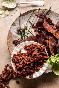 bacon and lettuce are on a plate next to some other food items with spoons