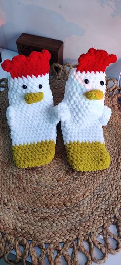 two knitted chickens sitting on top of a mat