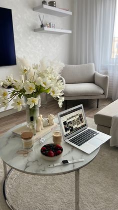 a laptop computer sitting on top of a table next to a vase filled with flowers