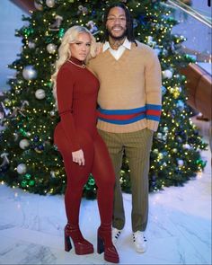 a man and woman standing in front of a christmas tree