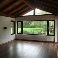 an empty room with wood floors and large windows looking out onto a lush green field