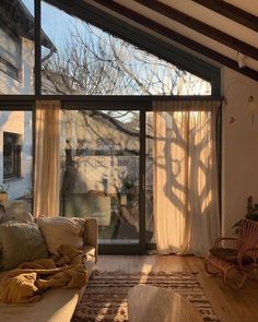 the sun shines through two large windows into a living room with wood flooring