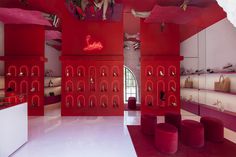 the interior of a shoe store with red walls and purple stools on the floor