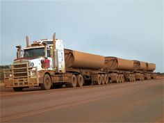 a large semi truck carrying an enormous load on it's back down the road