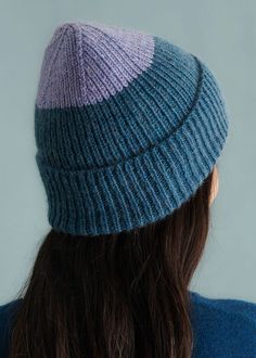 a woman with long hair wearing a blue and purple knitted hat on top of her head