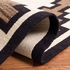 a close up view of a rug on the floor with wood floors and black and white stripes