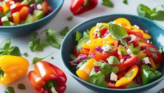 two blue bowls filled with colorful vegetables on top of a white tablecloth next to green and red peppers